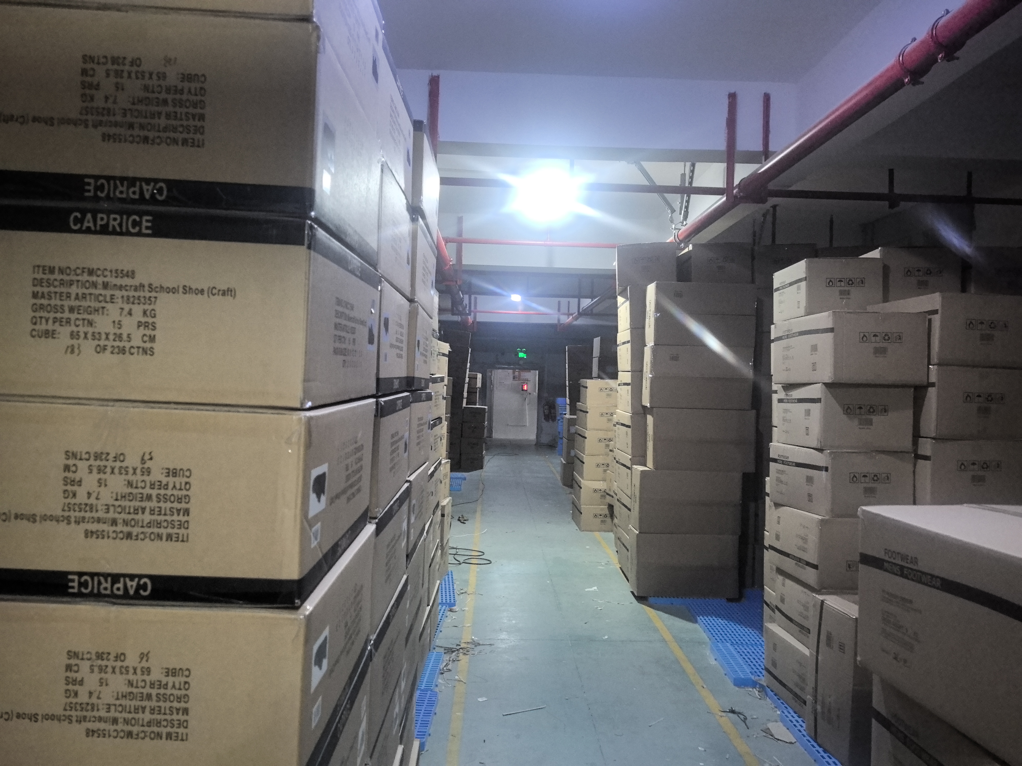 Finished-goods warehouse aisle stacked with labeled export shoe cartons