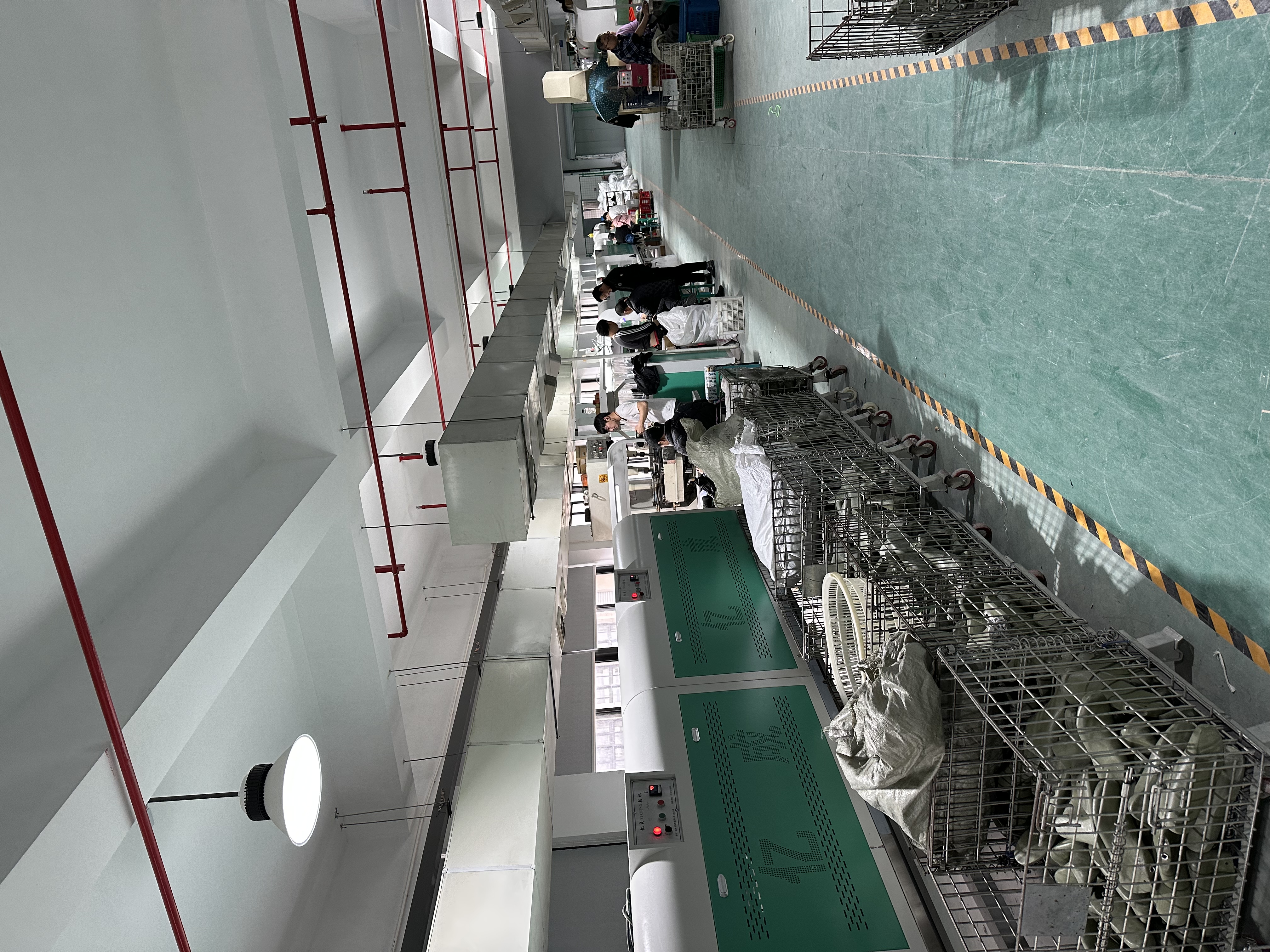 Interior view of the stitching workshop with sewing stations and finished uppers on wire trolleys